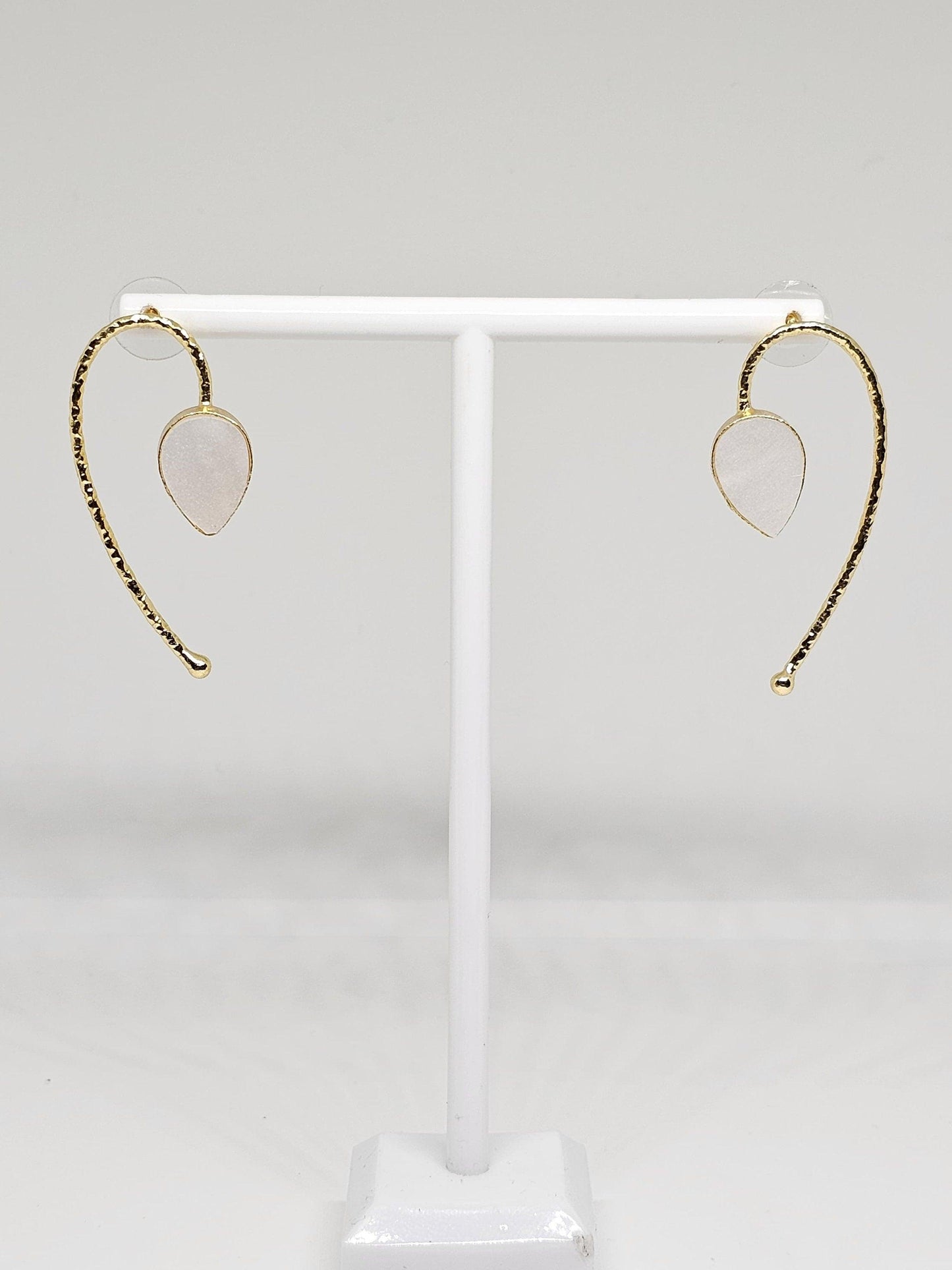 Close-up of unique brass and white stone curved dangle earrings with secure backings, perfect for special occasions and everyday wear