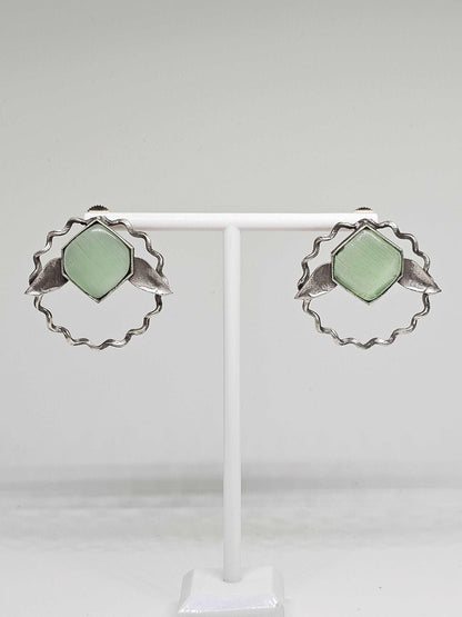 A pair of handcrafted lightweight brass stud earrings adorned with vibrant green Monalisa stones, designed in an elegant leaf shape, perfect for adding a touch of nature-inspired sophistication to any ensemble.