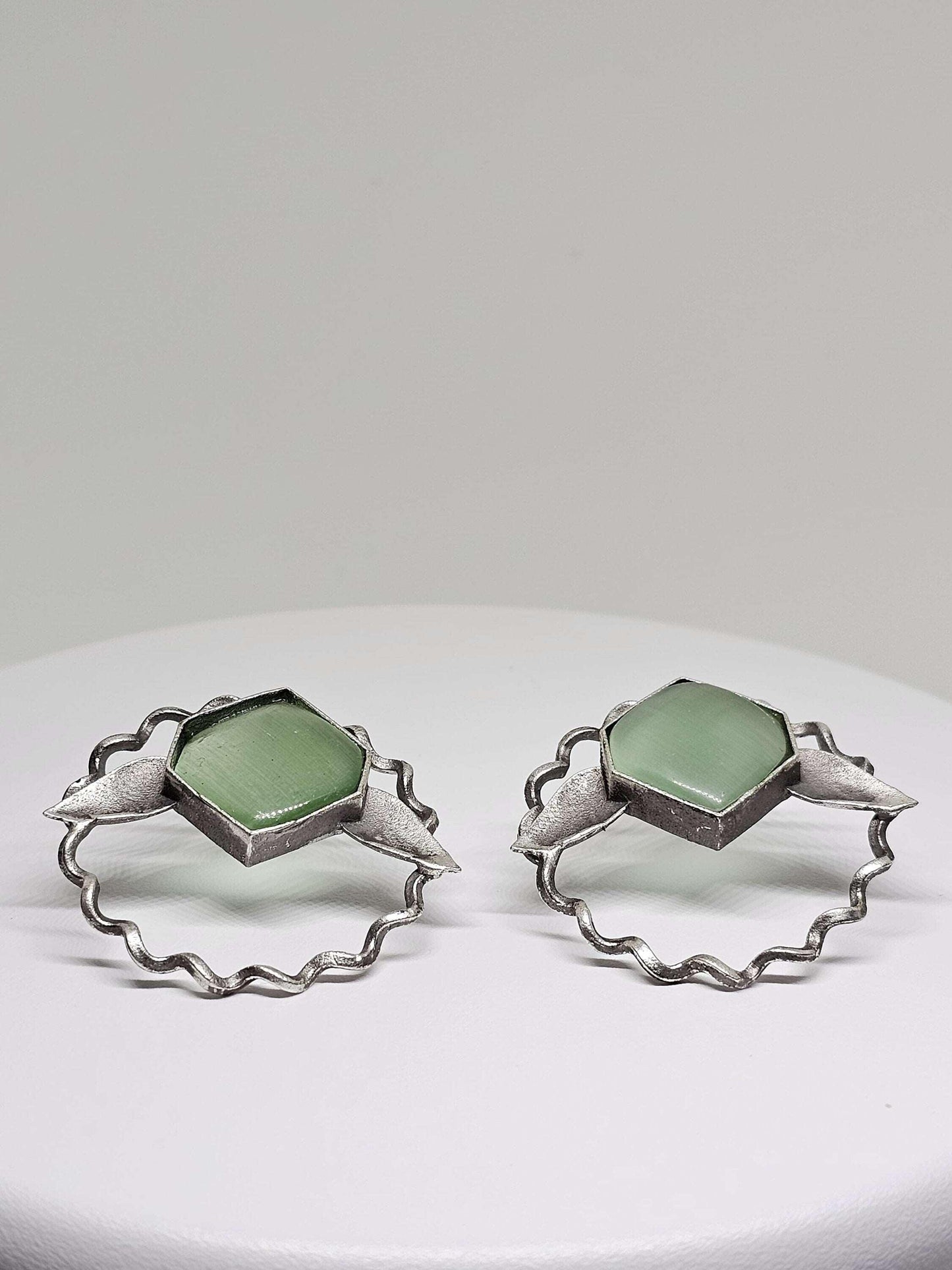 Elegant and lightweight brass leaf-shaped stud earrings featuring striking green Monalisa stones, showcasing a chic and nature-inspired design ideal for both casual and formal wear.