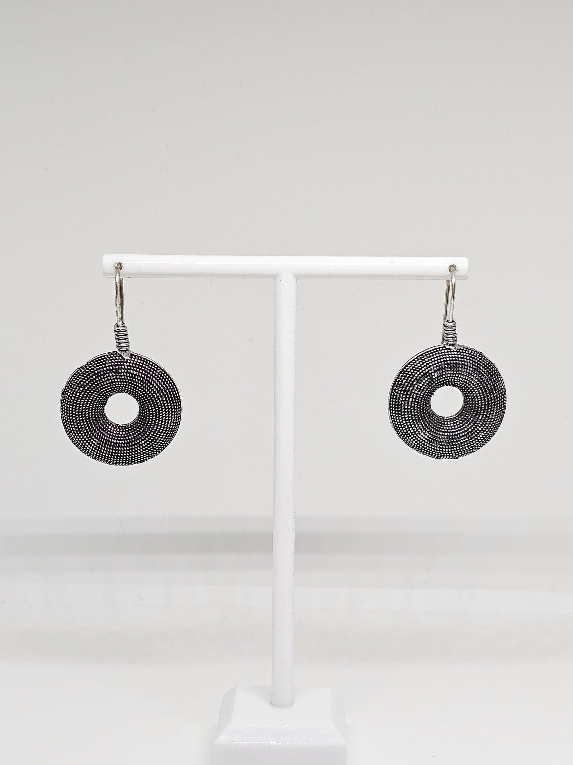 Handcrafted oxidised silver earrings featuring intricate circular design, displayed elegantly