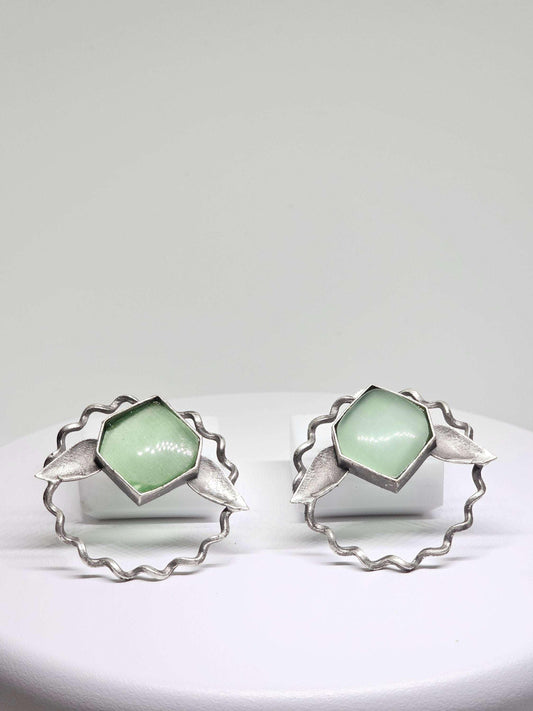 A pair of lightweight brass stud earrings featuring green Monalisa stones in a delicate leaf design, perfect for adding a touch of elegance and nature-inspired beauty to any outfit.