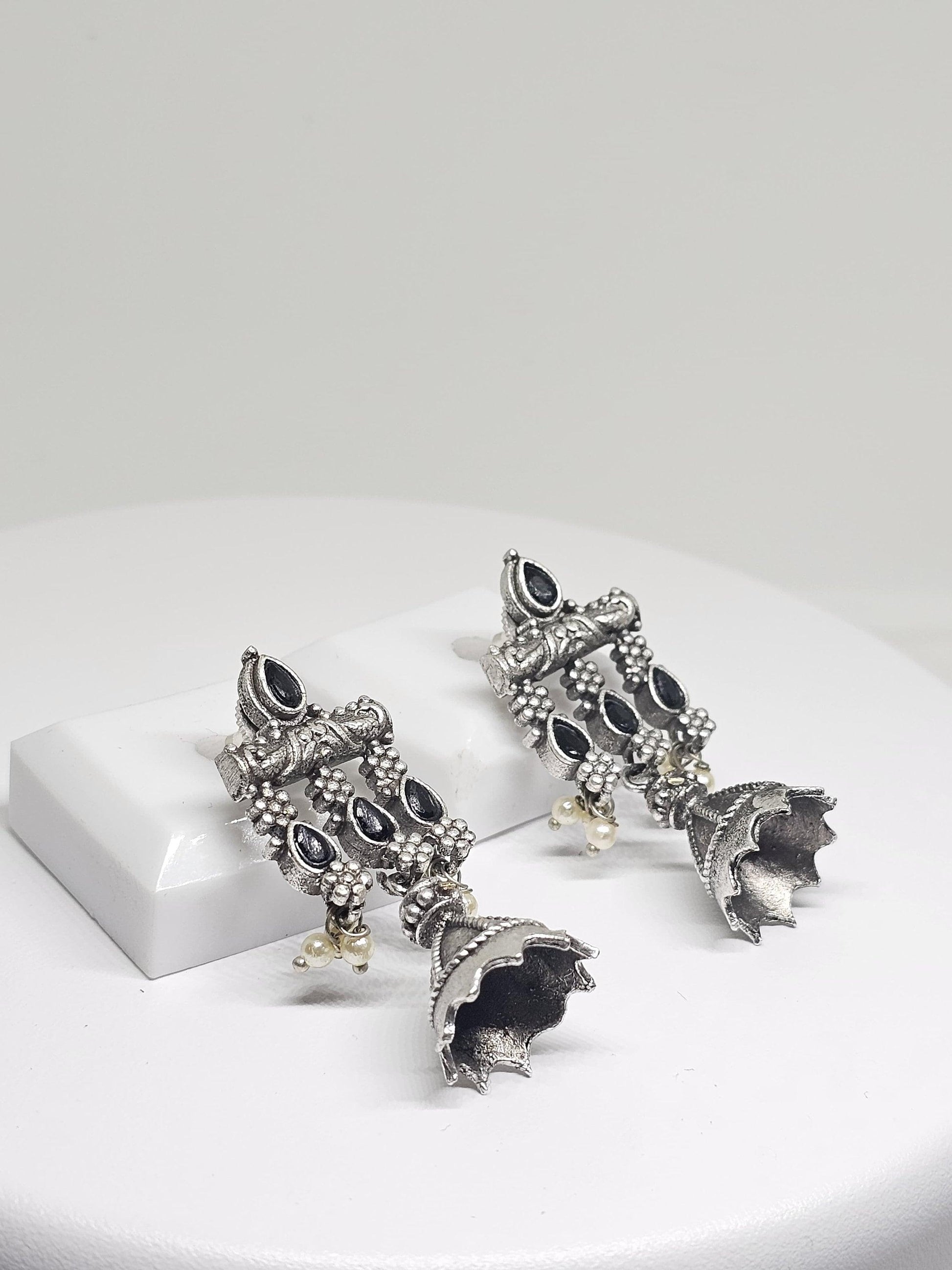 Close-up of oxidised silver earrings adorned with black stones and white pearls, showcasing a delicate Jhumka Jhumki style for elegant wear.