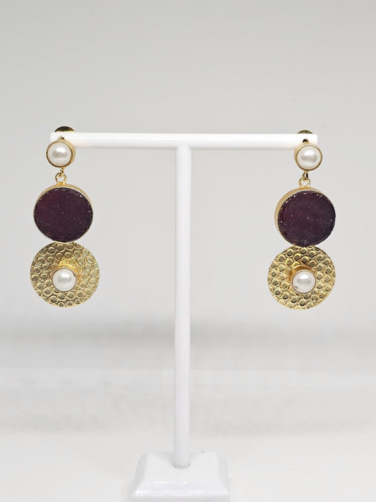 Elegant gold-plated earrings with purple stone and pearl accents shown in close-up on a display stand