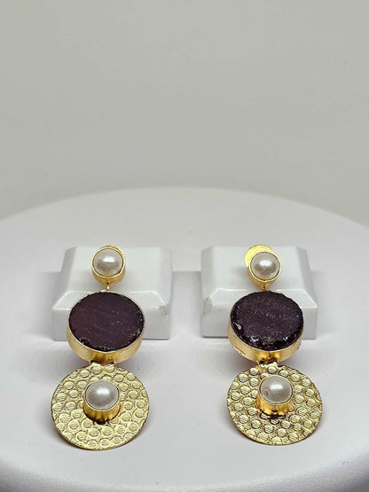 Handmade gold-plated double drop earrings featuring a purple stone and pearl accents displayed on a white stand