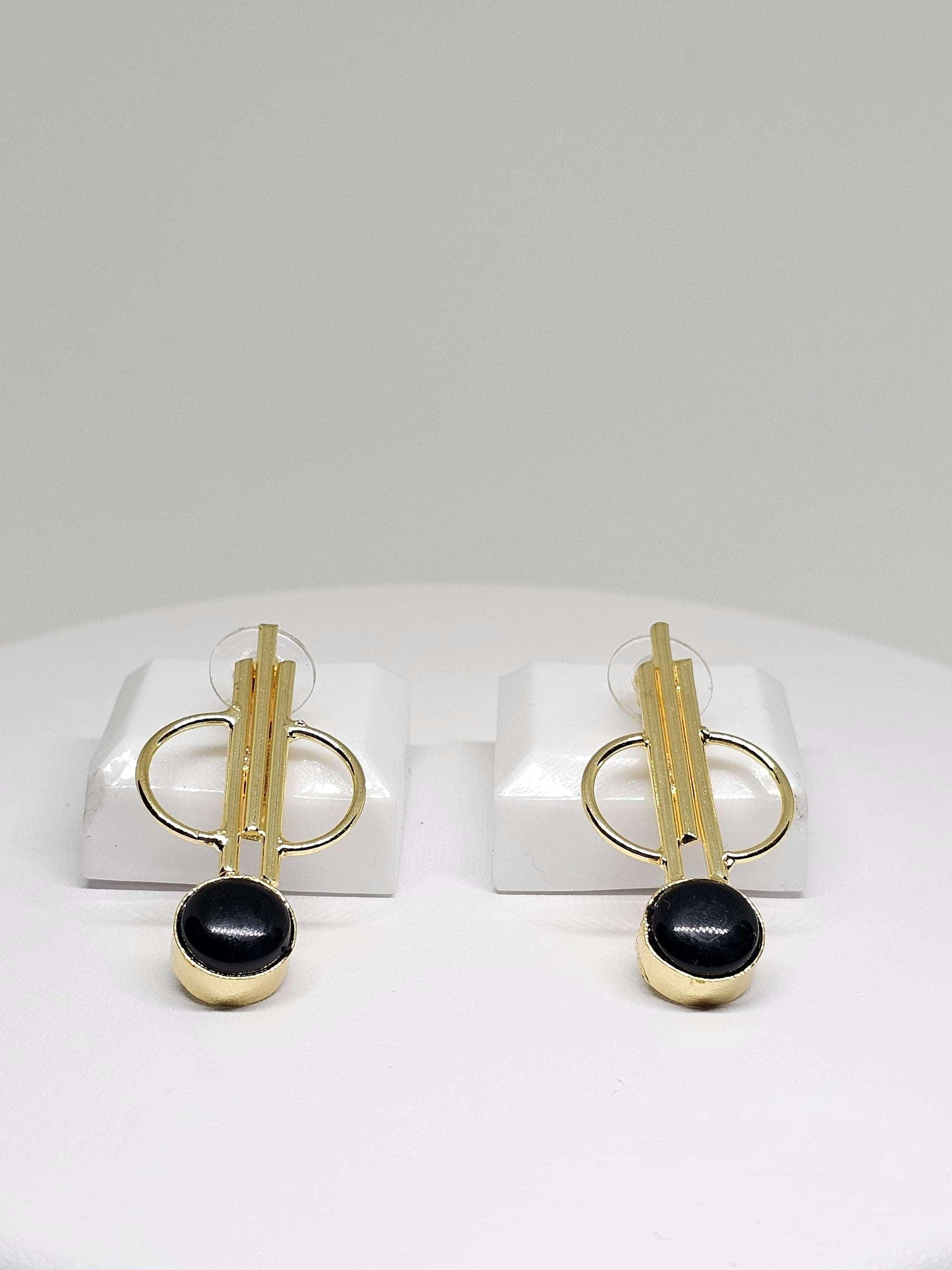 Unique gold and natural stone earrings displayed on a stand, featuring an artistic design with natural stone elements and brass, perfect for adding a creative and stylish touch to any ensemble