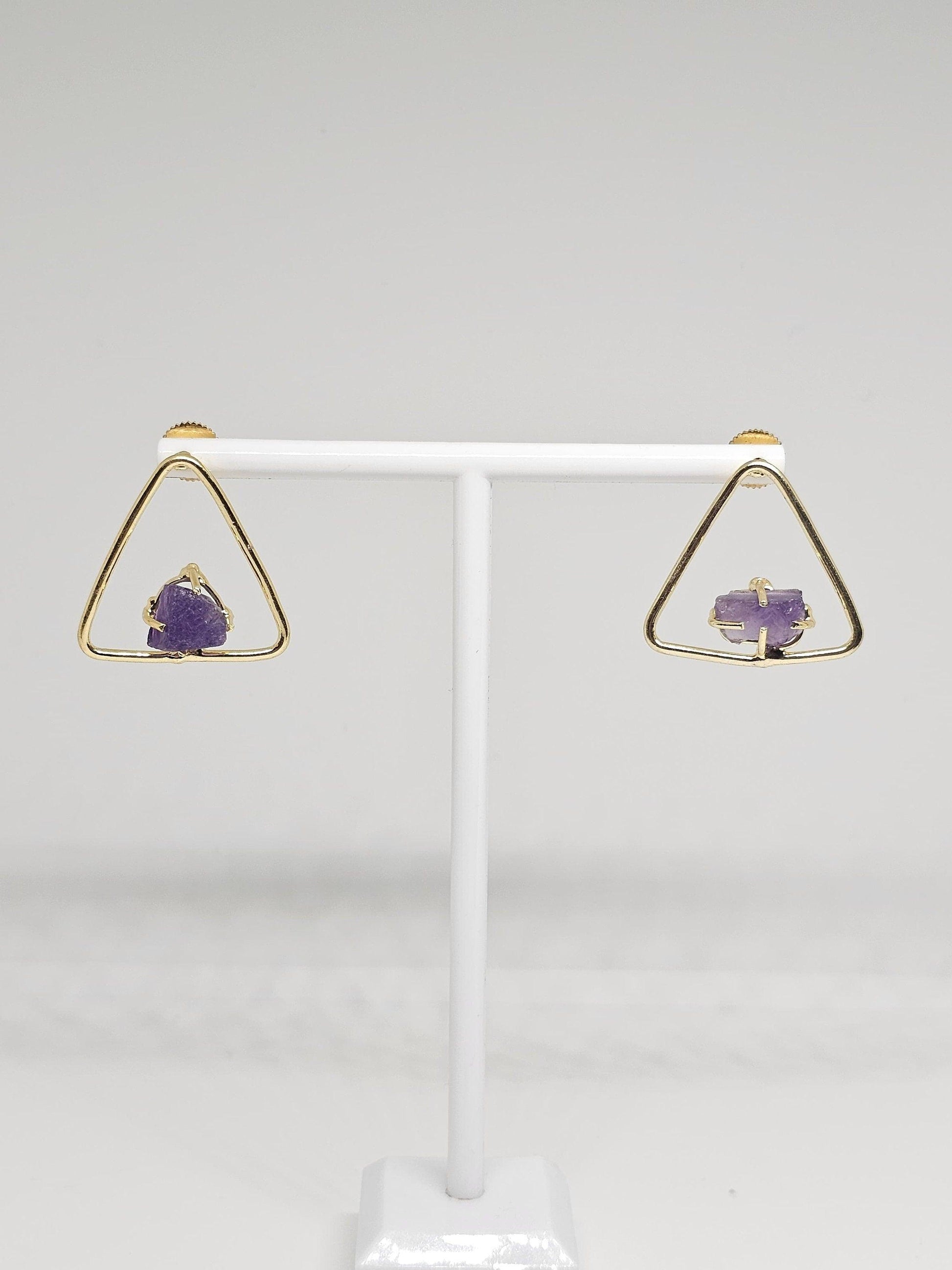 Detailed view of brass triangle earrings featuring raw amethyst stones, combining modern geometric design with the organic beauty of amethyst