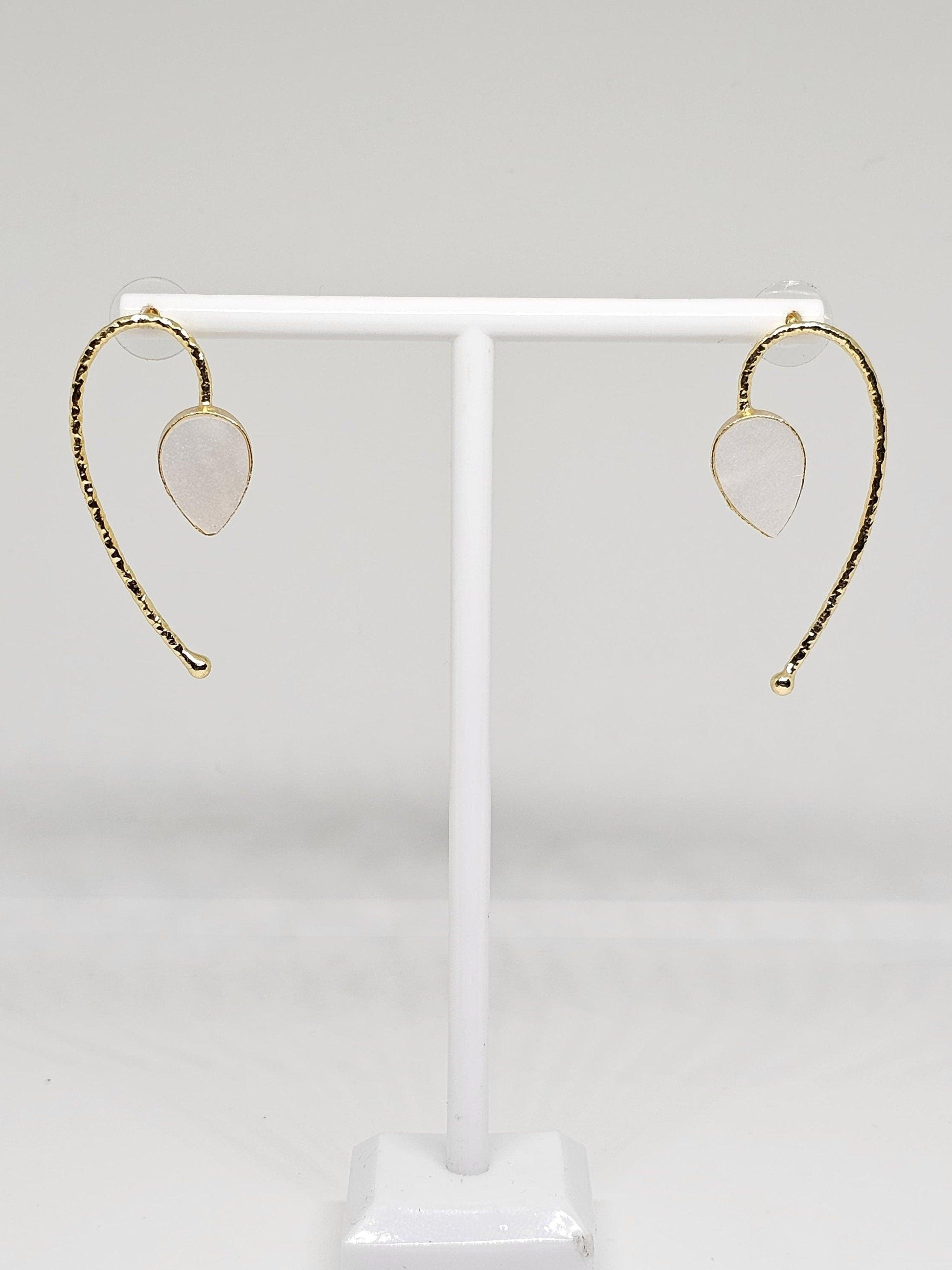 Close-up of unique brass and white stone curved dangle earrings with secure backings, perfect for special occasions and everyday wear