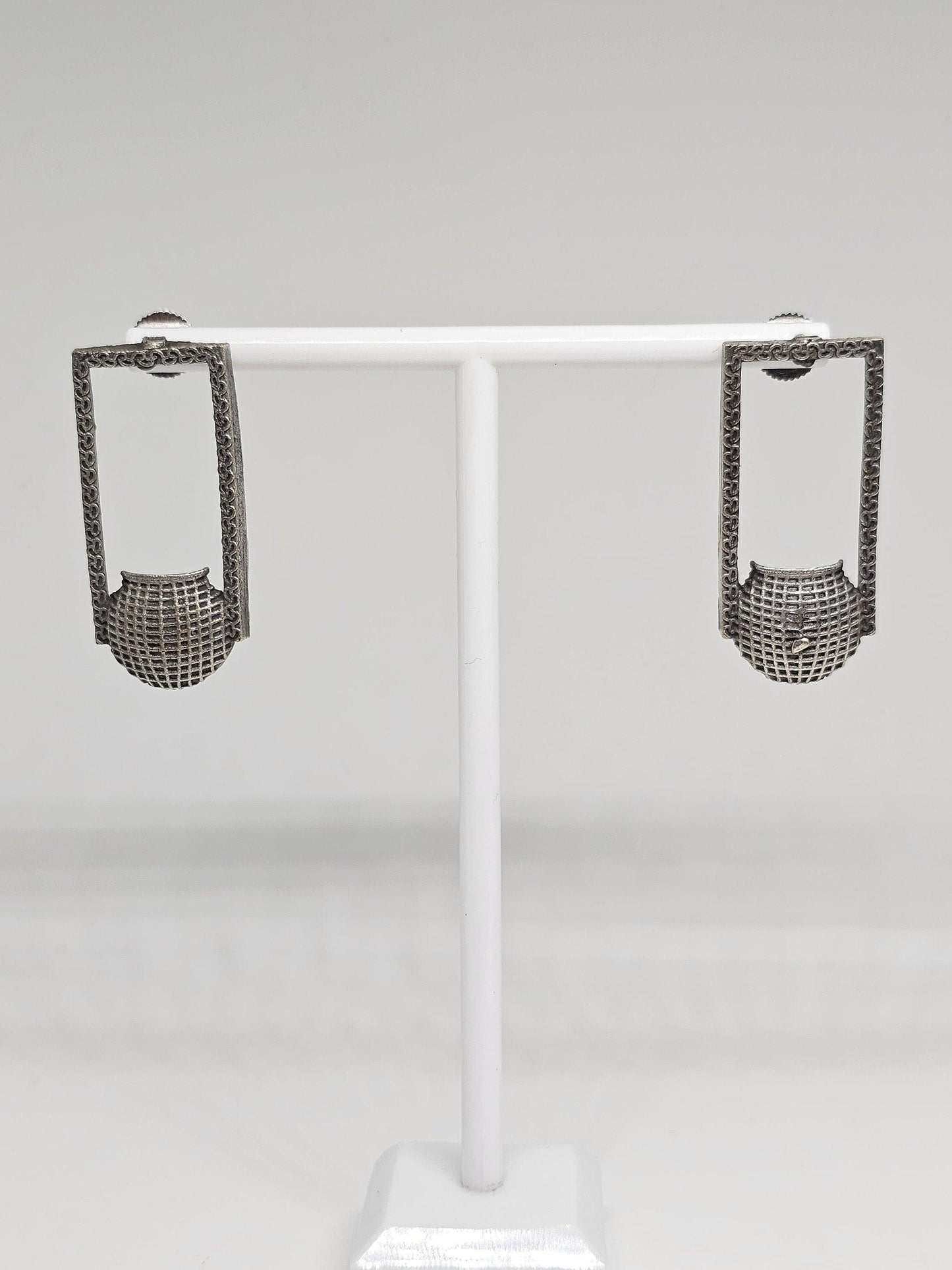 Close-up of unique silver geometric earrings with intricate patterns, handcrafted ethnic fashion accessory