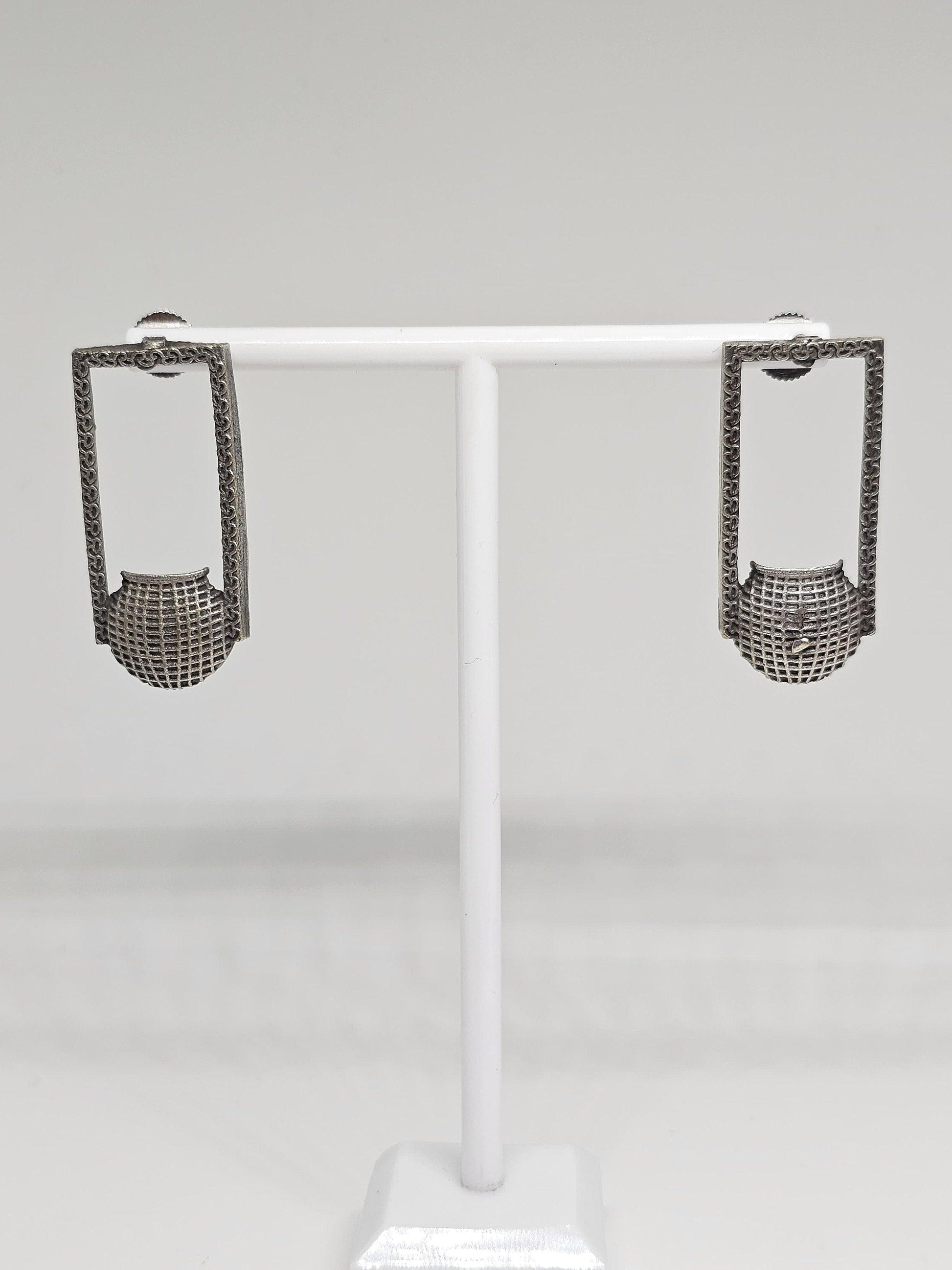 Close-up of unique silver geometric earrings with intricate patterns, handcrafted ethnic fashion accessory