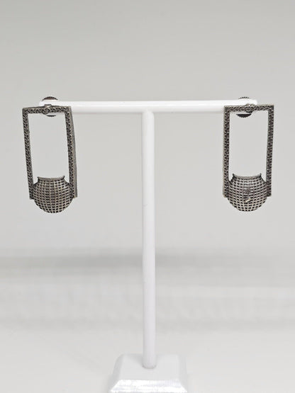 Close-up of unique silver geometric earrings with intricate patterns, handcrafted ethnic fashion accessory