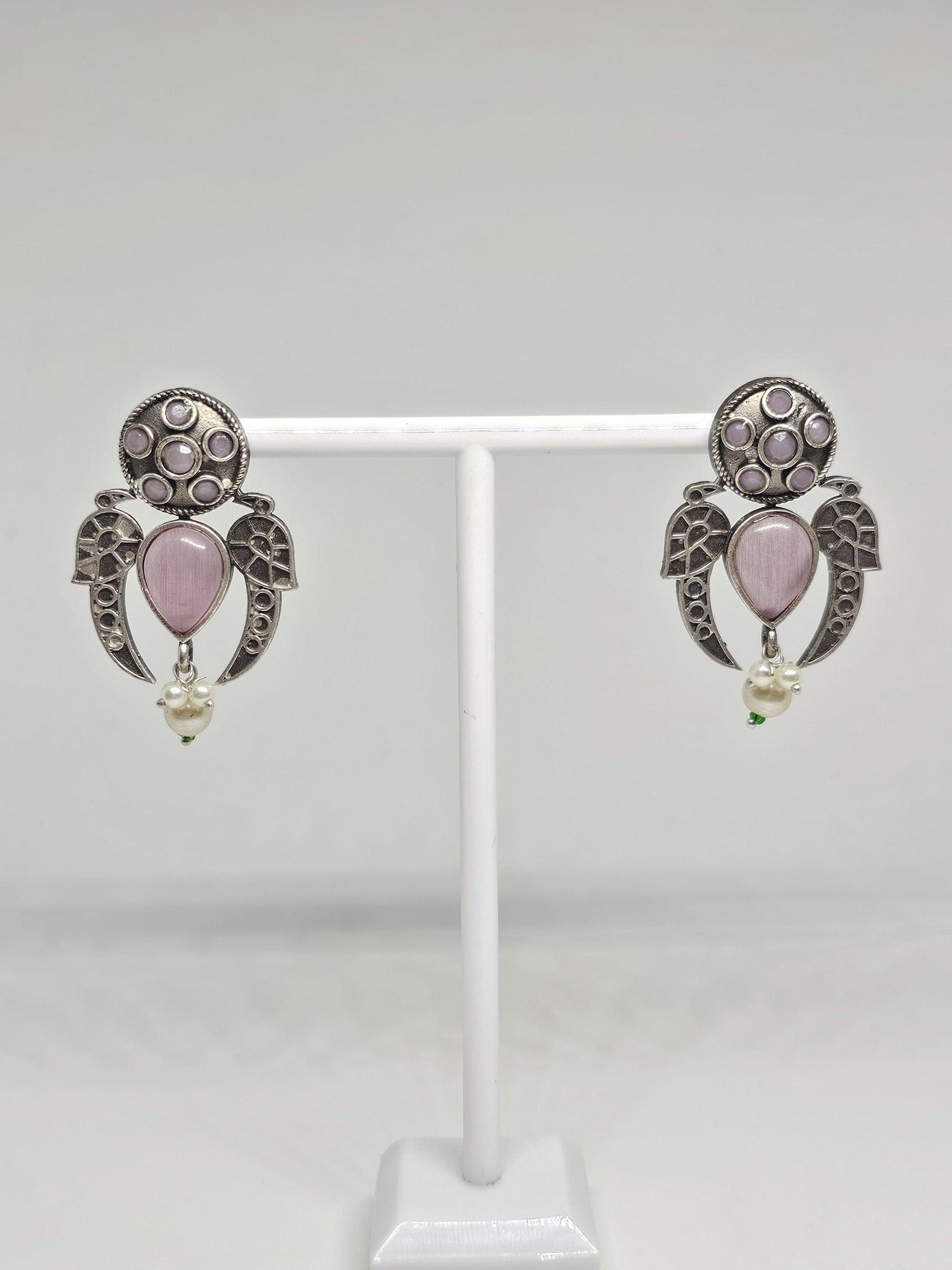 Handcrafted ethnic earrings with intricate silver details, pink stones, and dangling pearls