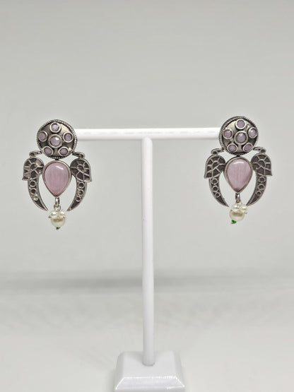 Handcrafted ethnic earrings with intricate silver details, pink stones, and dangling pearls