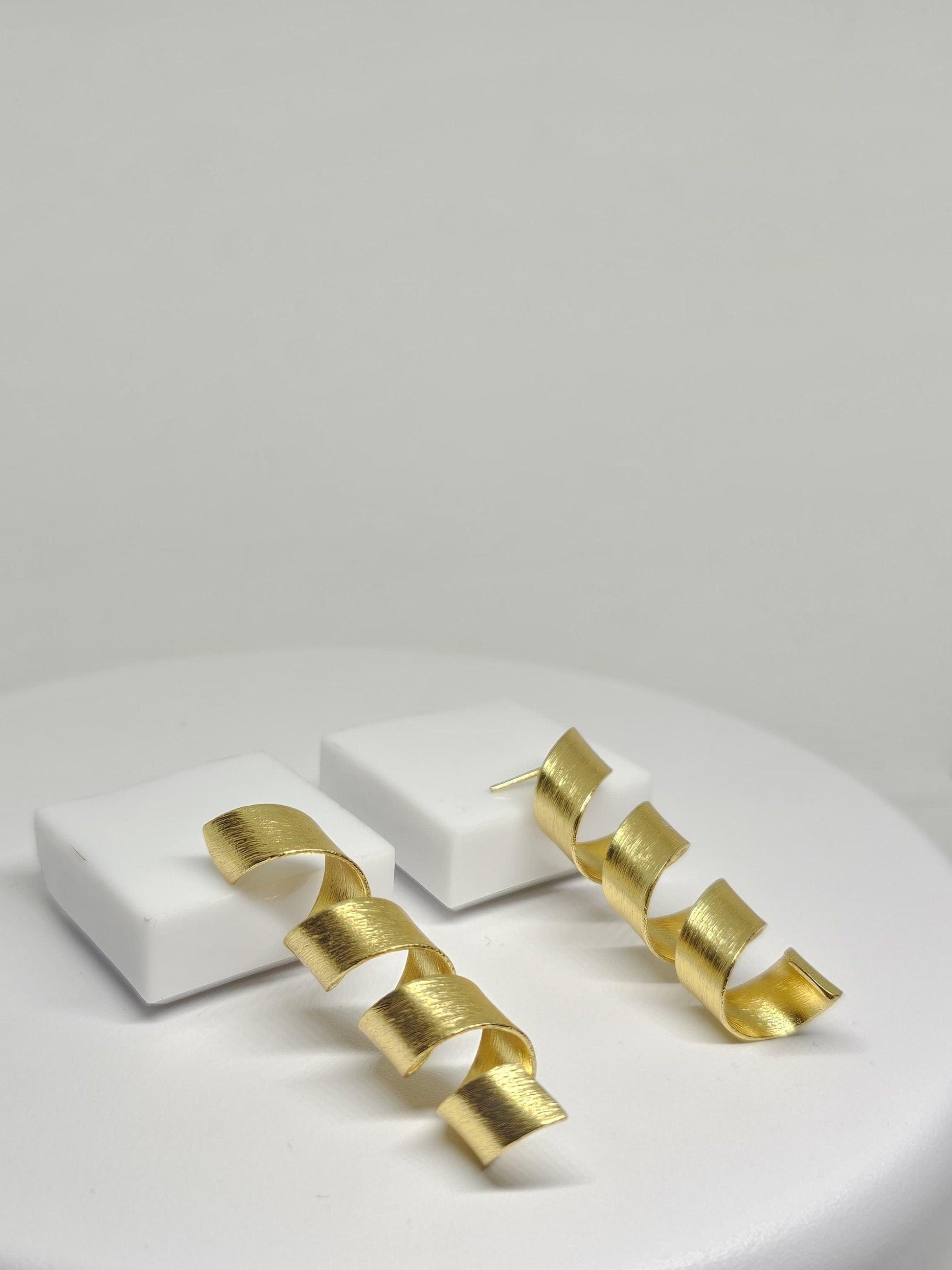 Modern gold-toned spiral drop earrings with a matte finish, featuring a stylish helix design.