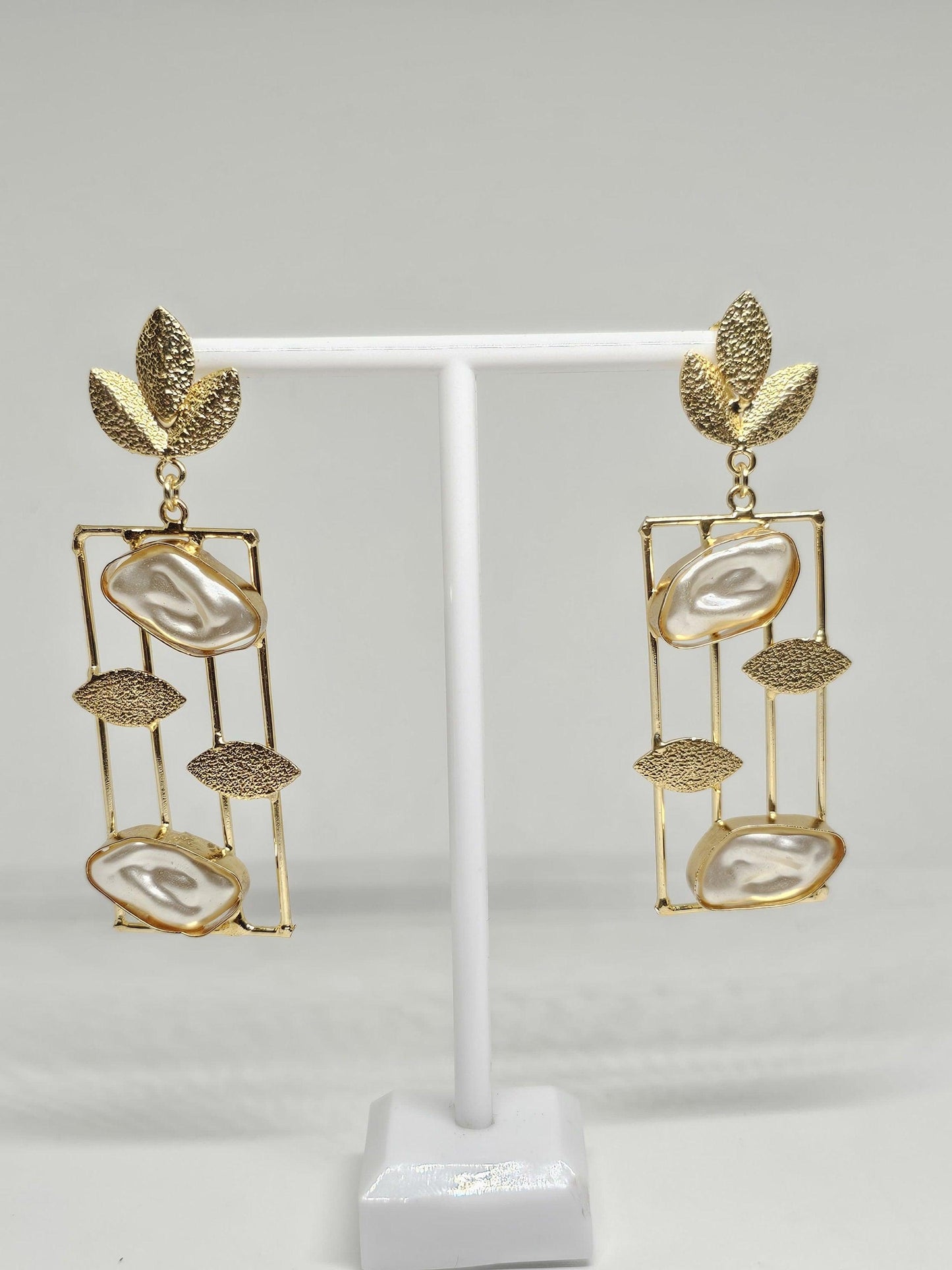Gold-plated drop earrings with mother of pearl stones, geometric frame, and leaf accents