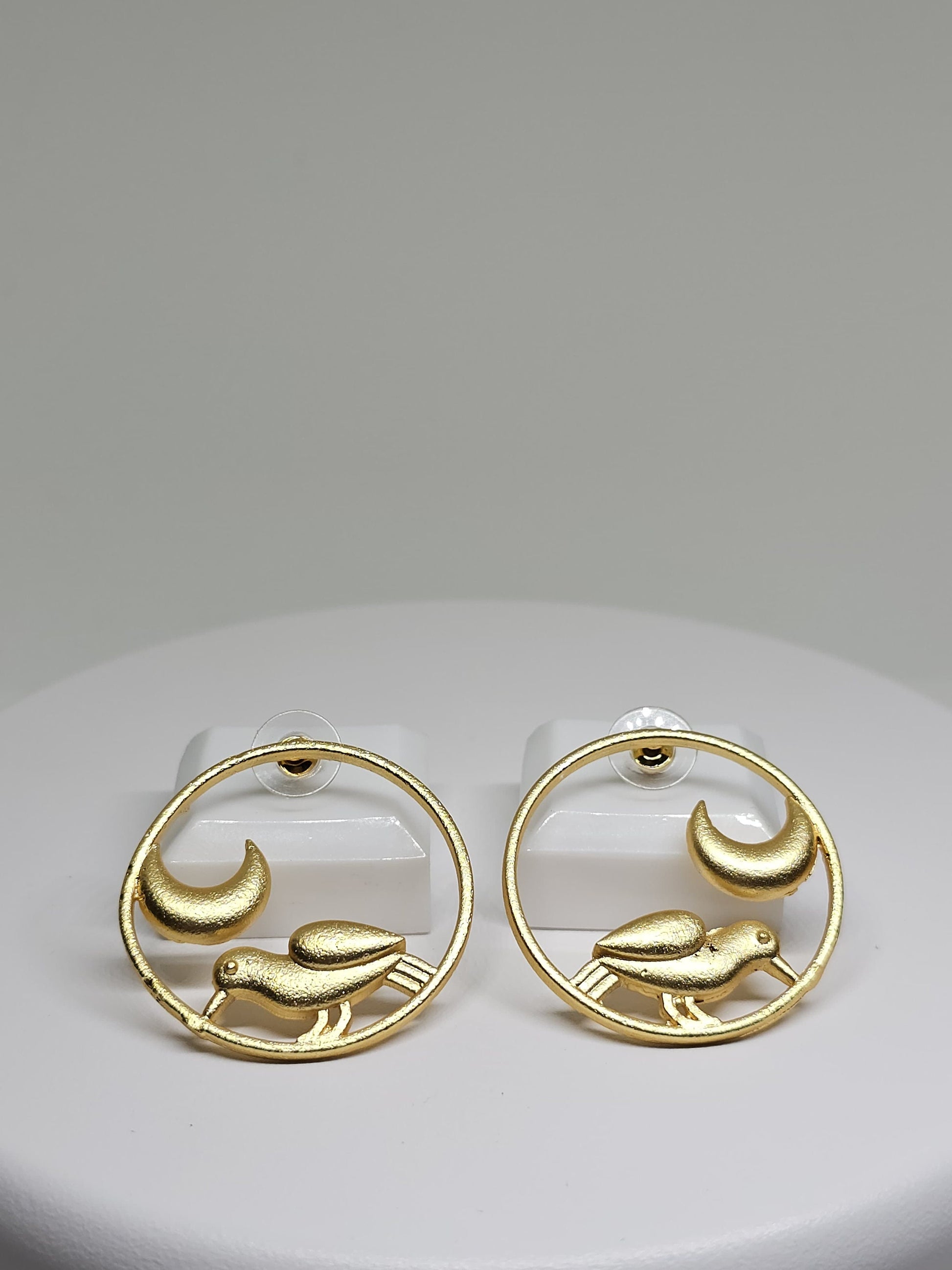 Side view of minimalist bird and crescent moon brass hoop earrings