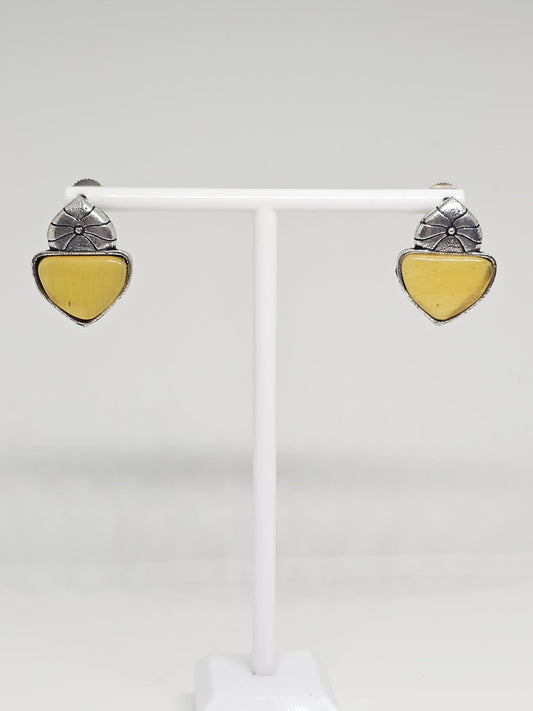 Close-up of silver-tone stud earrings with floral design and Yellow stone accent.