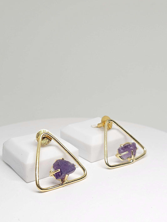 Close-up of elegant triangle brass earrings adorned with raw amethyst stones, highlighting the modern geometric design and natural purple hues