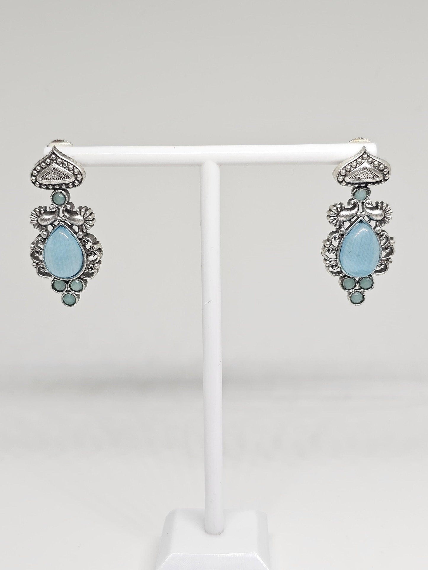 Antique-style silver earrings with teardrop and circular blue stones.