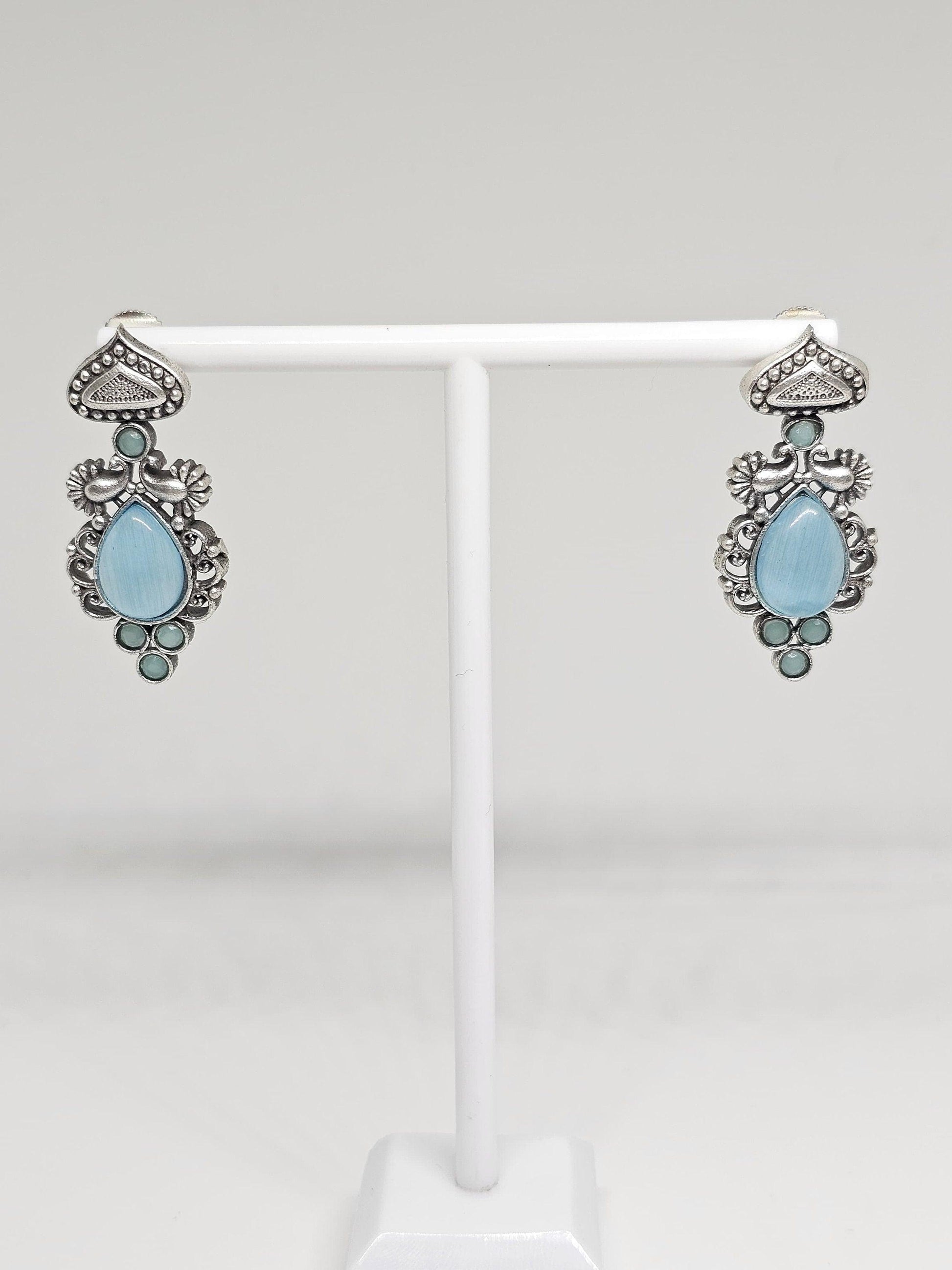 Antique-style silver earrings with teardrop and circular blue stones.