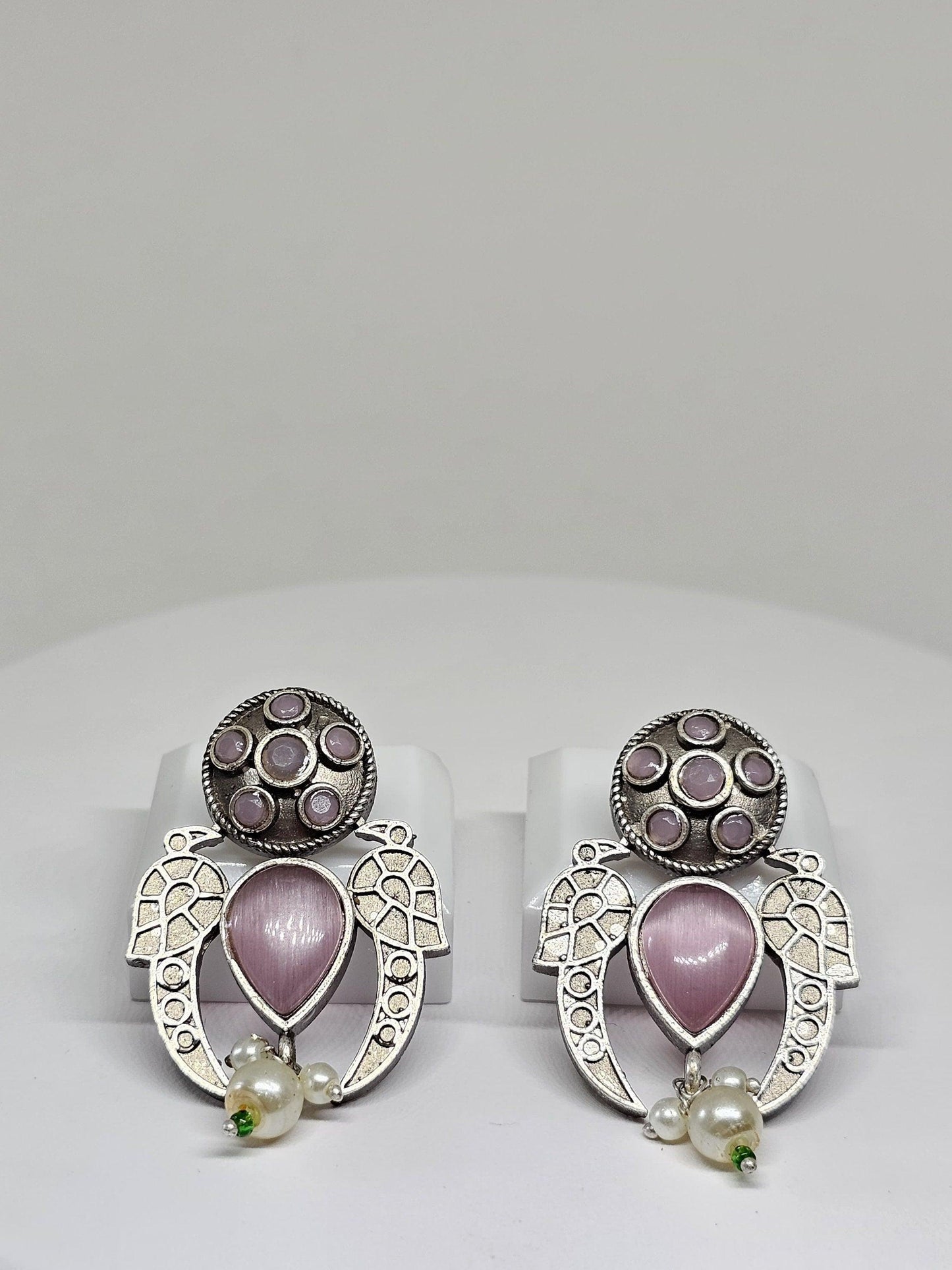 Boho-style silver earrings featuring pink gemstones and pearl dangles on a white background