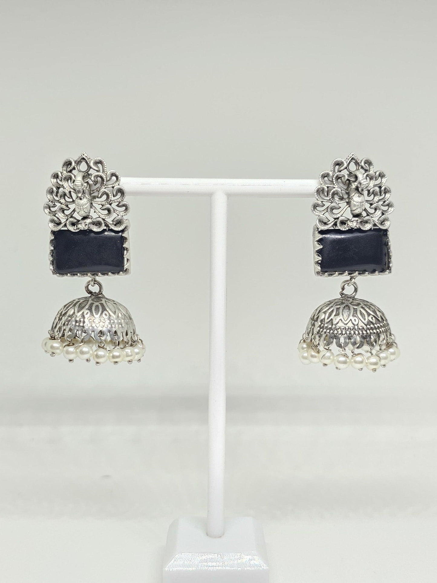 Silver jhumka earrings with black stone and pearl accents on white background