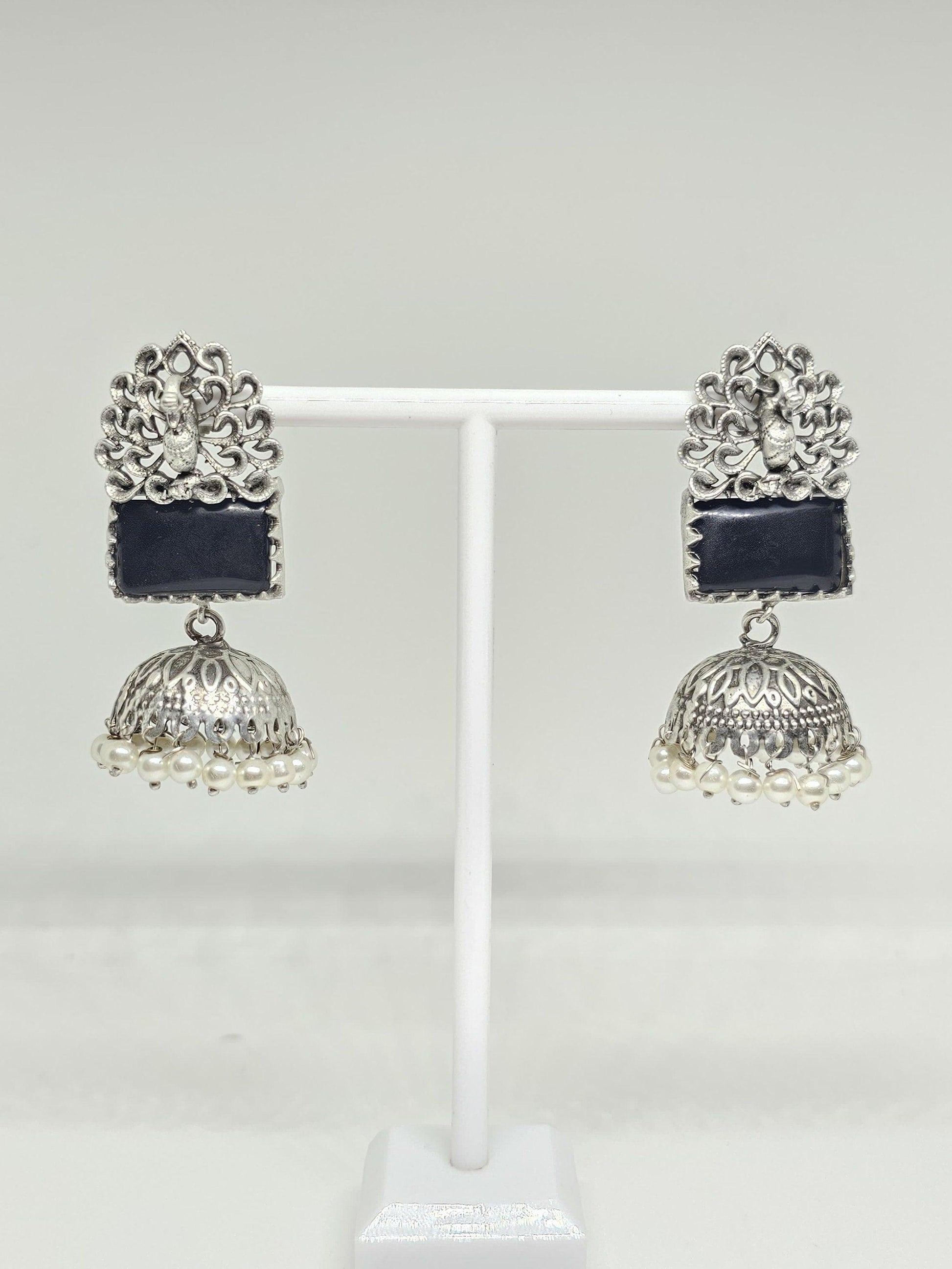 Silver jhumka earrings with black stone and pearl accents on white background