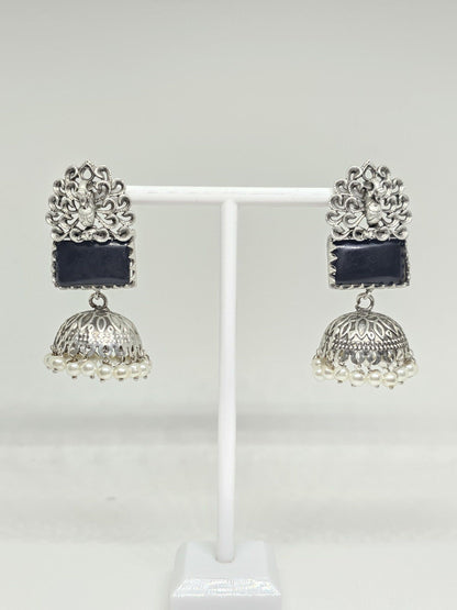 Silver jhumka earrings with black stone and pearl accents on white background