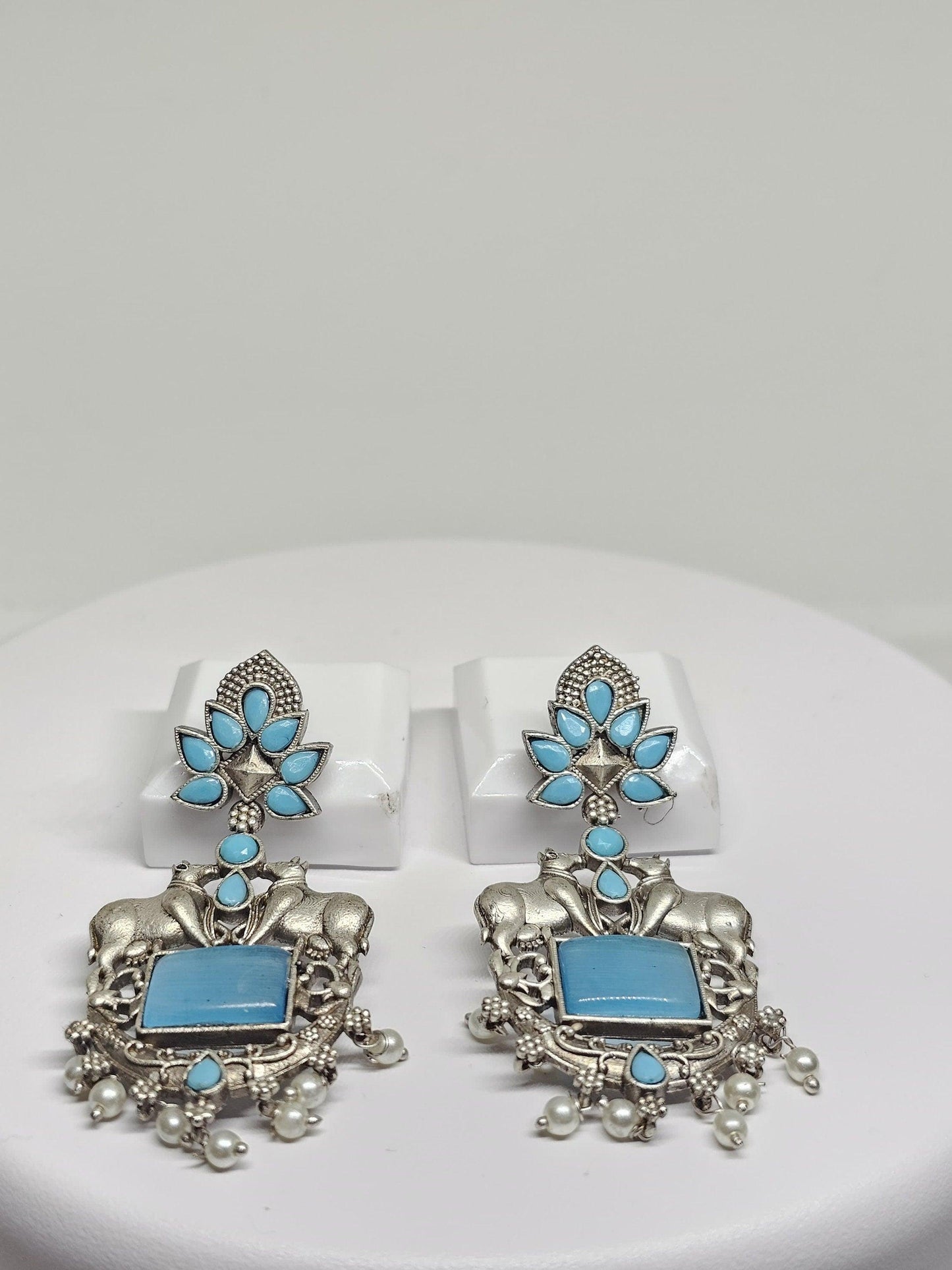 Traditional oxidized silver earrings with bull motifs, floral designs, and pearl drops