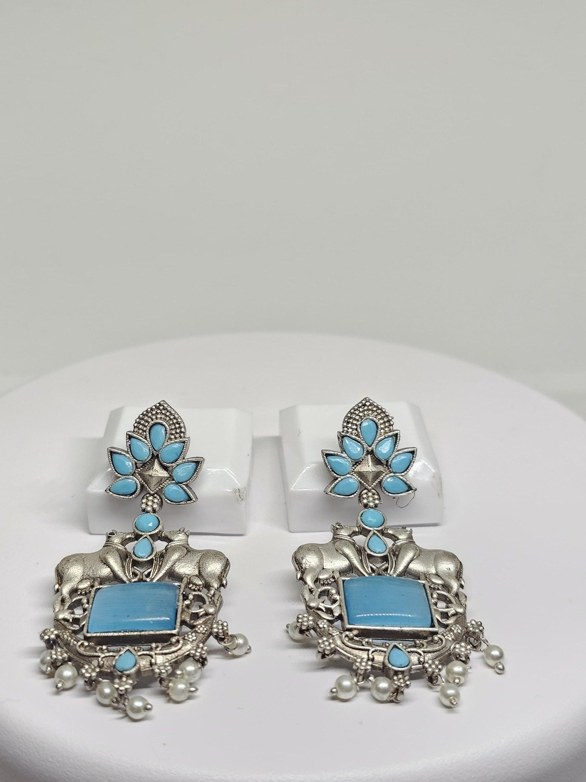 Traditional oxidized silver earrings with bull motifs, floral designs, and pearl drops