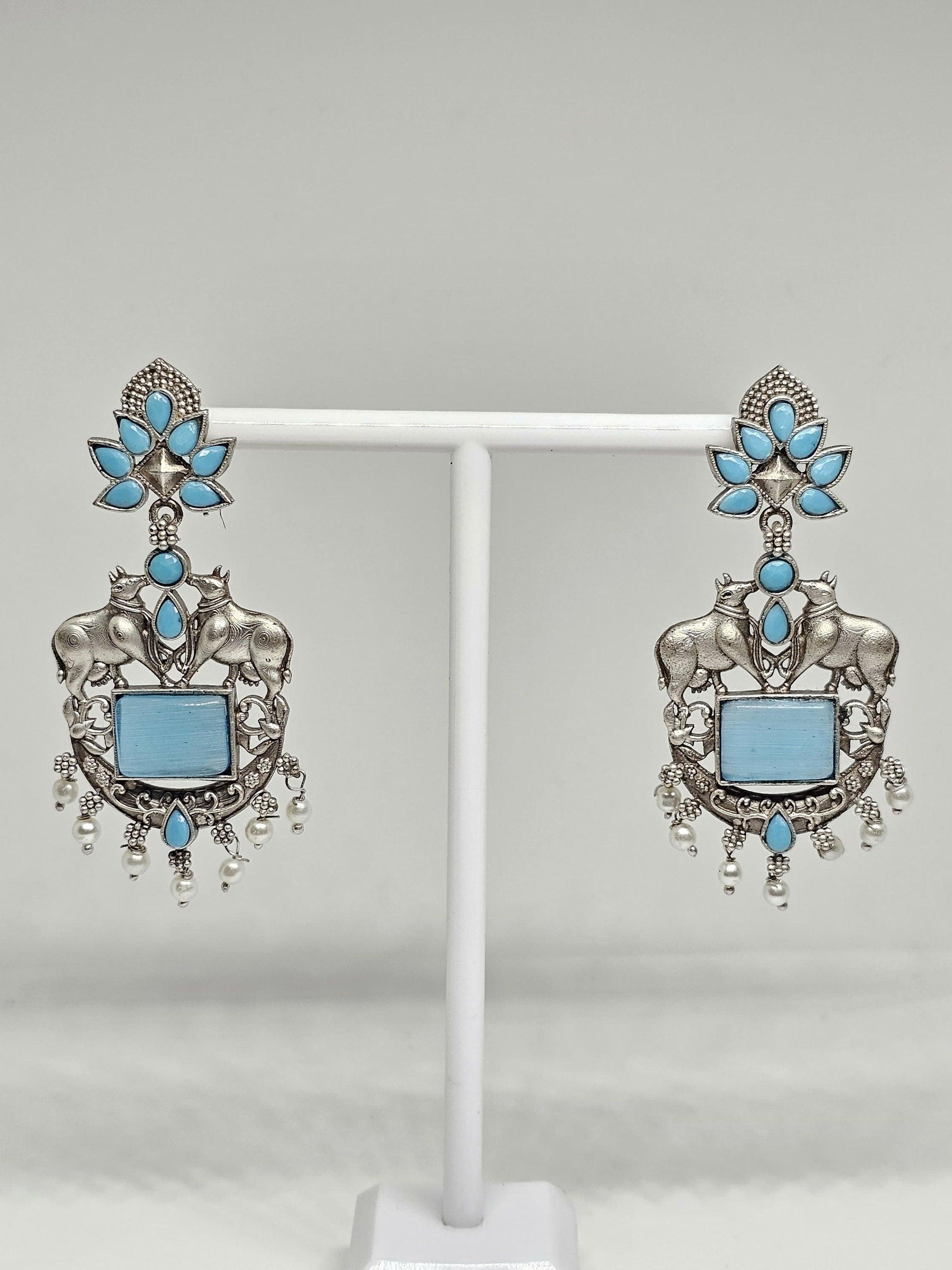 Oxidized silver earrings with bull motifs, blue stones, floral designs, and pearl drop accents.