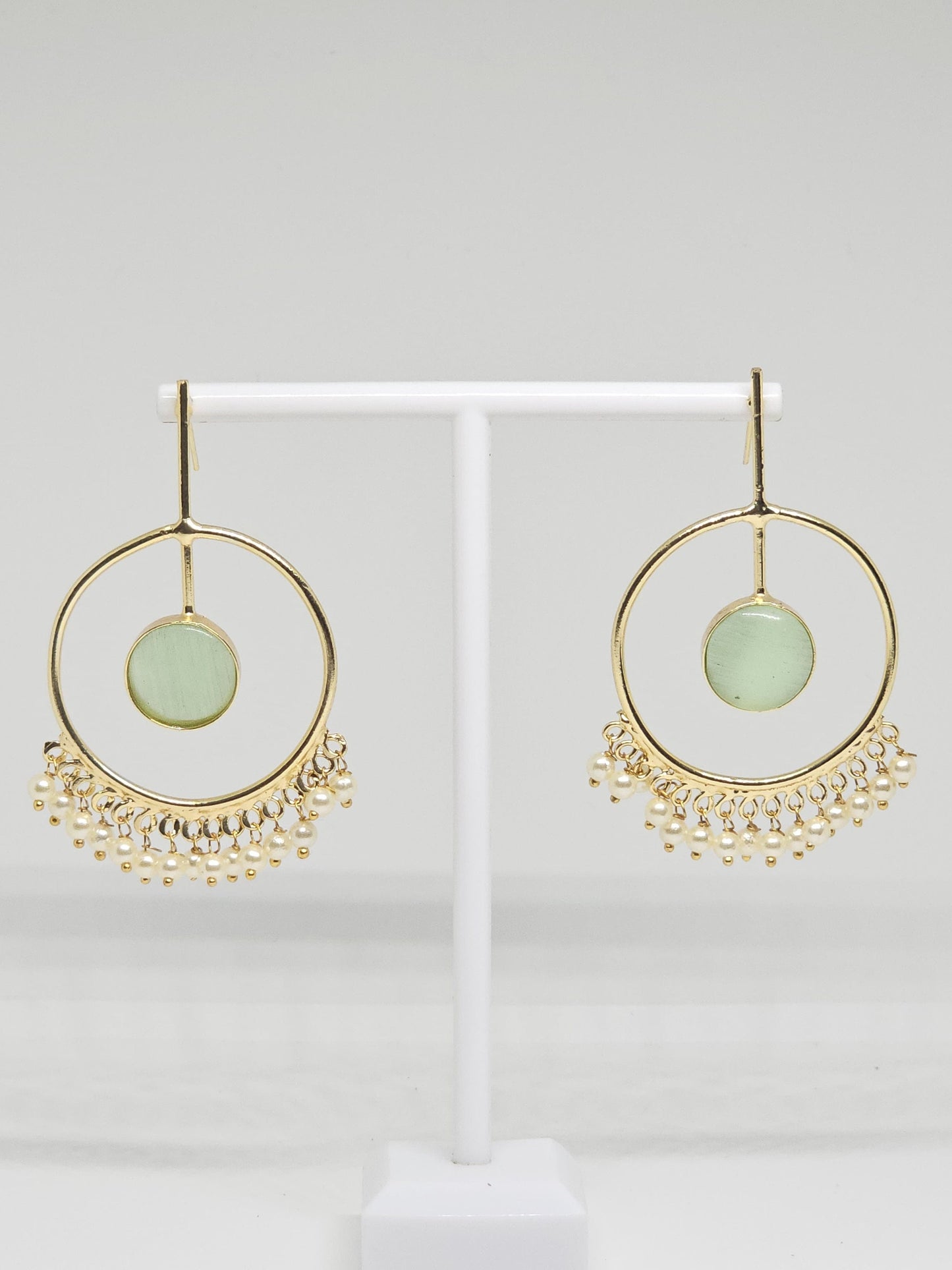 Gold-plated hoop earrings with green stone and pearl dangles on display