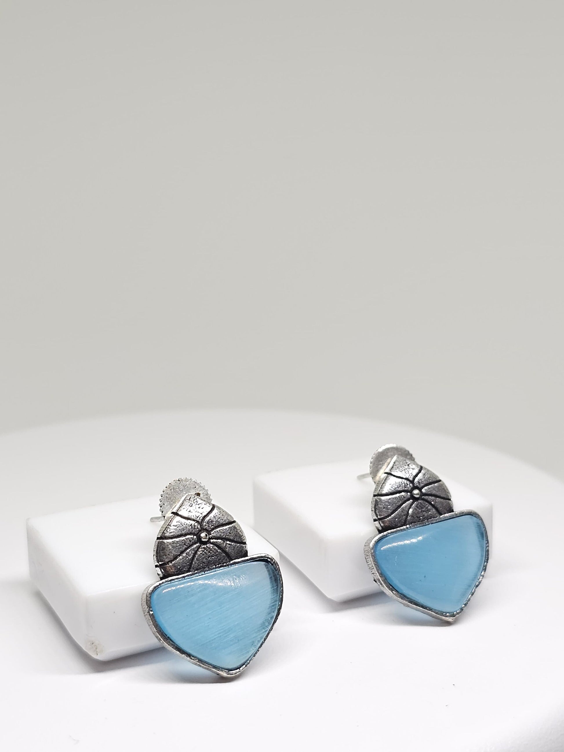 Side view of vintage-inspired silver-tone earrings with blue stone