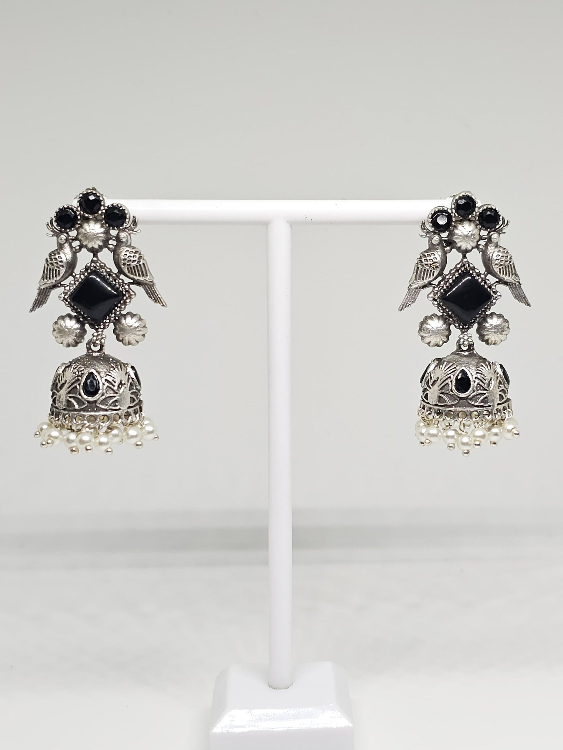 Handcrafted silver earrings with black stones, bird motif, and pearl accents