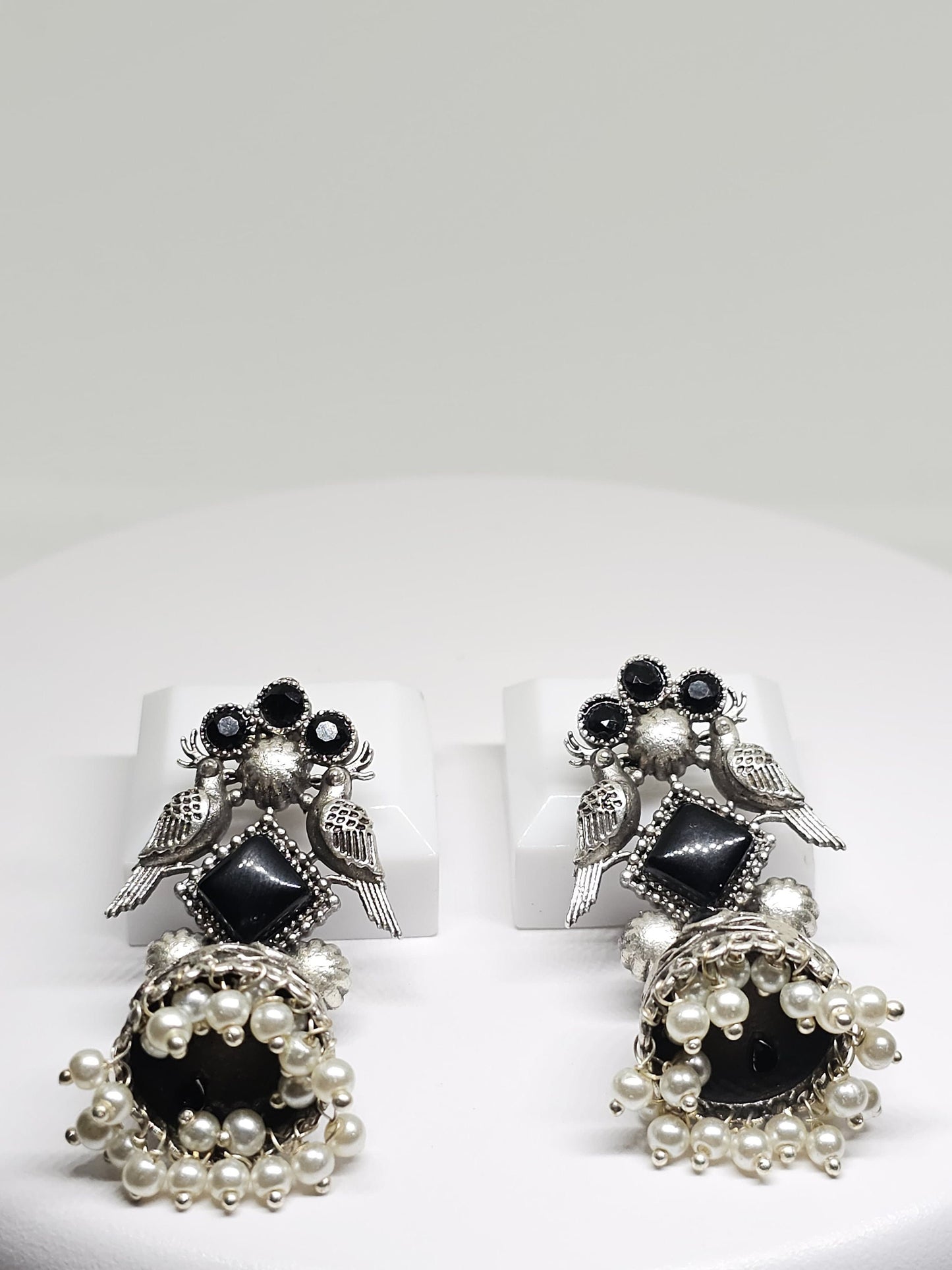 Silver earrings with black gems, bird design, and pearl dangles