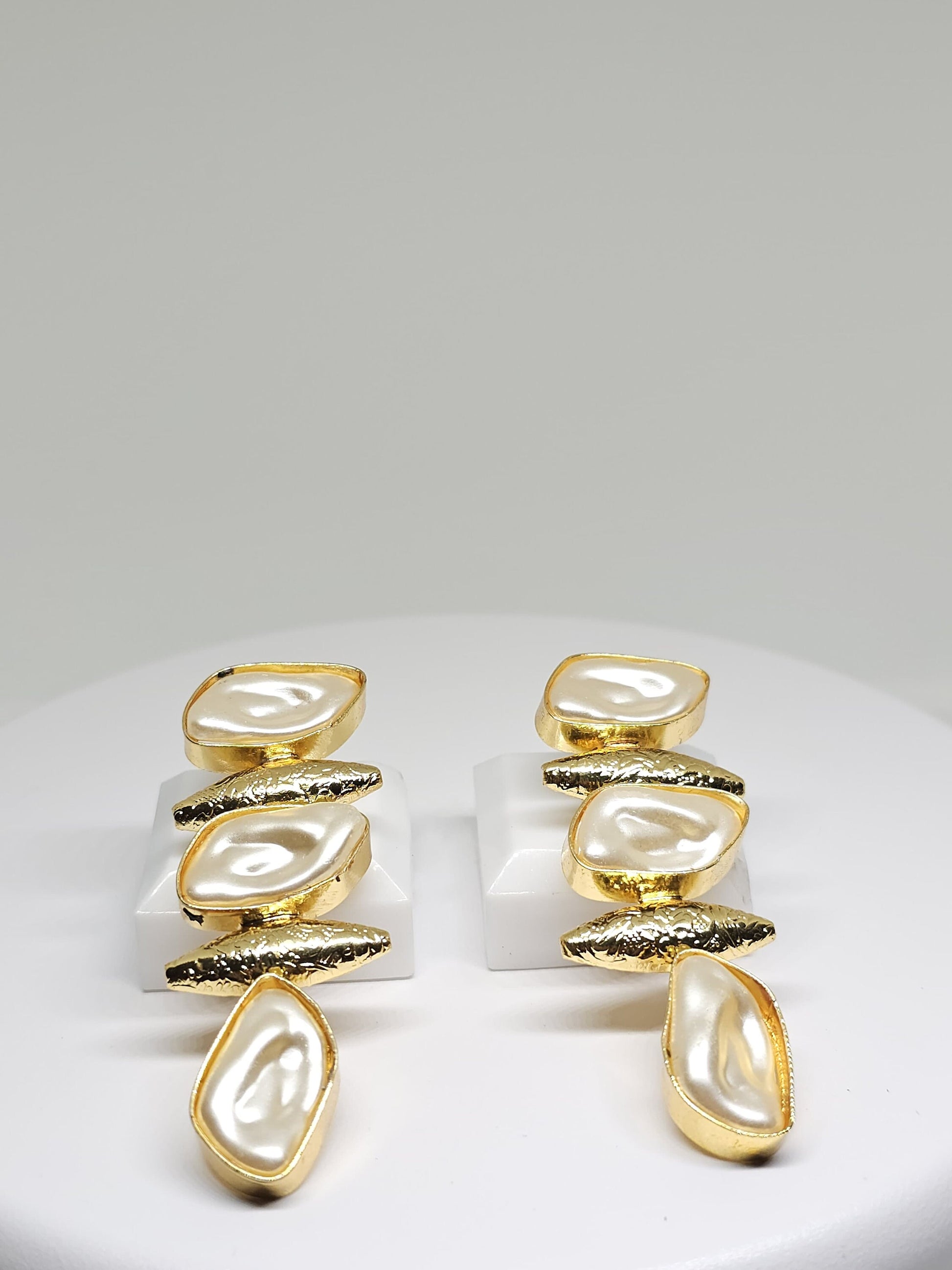 Close-up of luxurious gold-tone earrings with mother of pearl accents