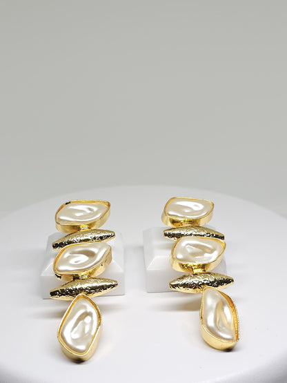 Close-up of luxurious gold-tone earrings with mother of pearl accents
