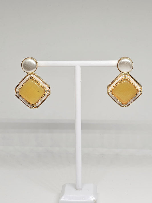 Elegant geometric drop earrings featuring a bright yellow stone centerpiece, framed with intricate gold beading and a pearl top design, perfect for modern statement jewelry lovers