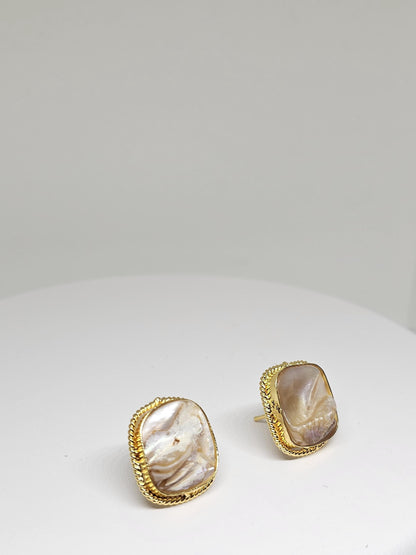 Close-up of gold-plated stud earrings with natural pearl shell