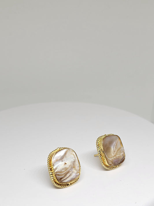 Close-up of gold-plated stud earrings with natural pearl shell
