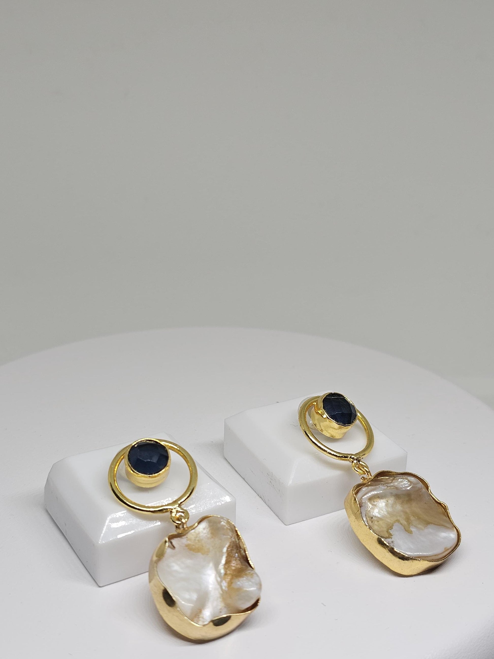 Handmade earrings featuring a unique pearl shell design and blue stone accent