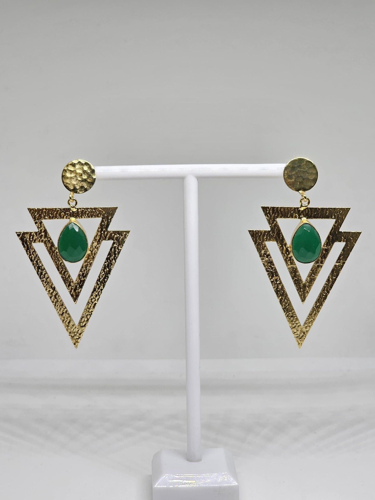 Geometric beaten brass earrings featuring layered textured triangles and a green teardrop-shaped stone, perfect for bohemian and statement looks
