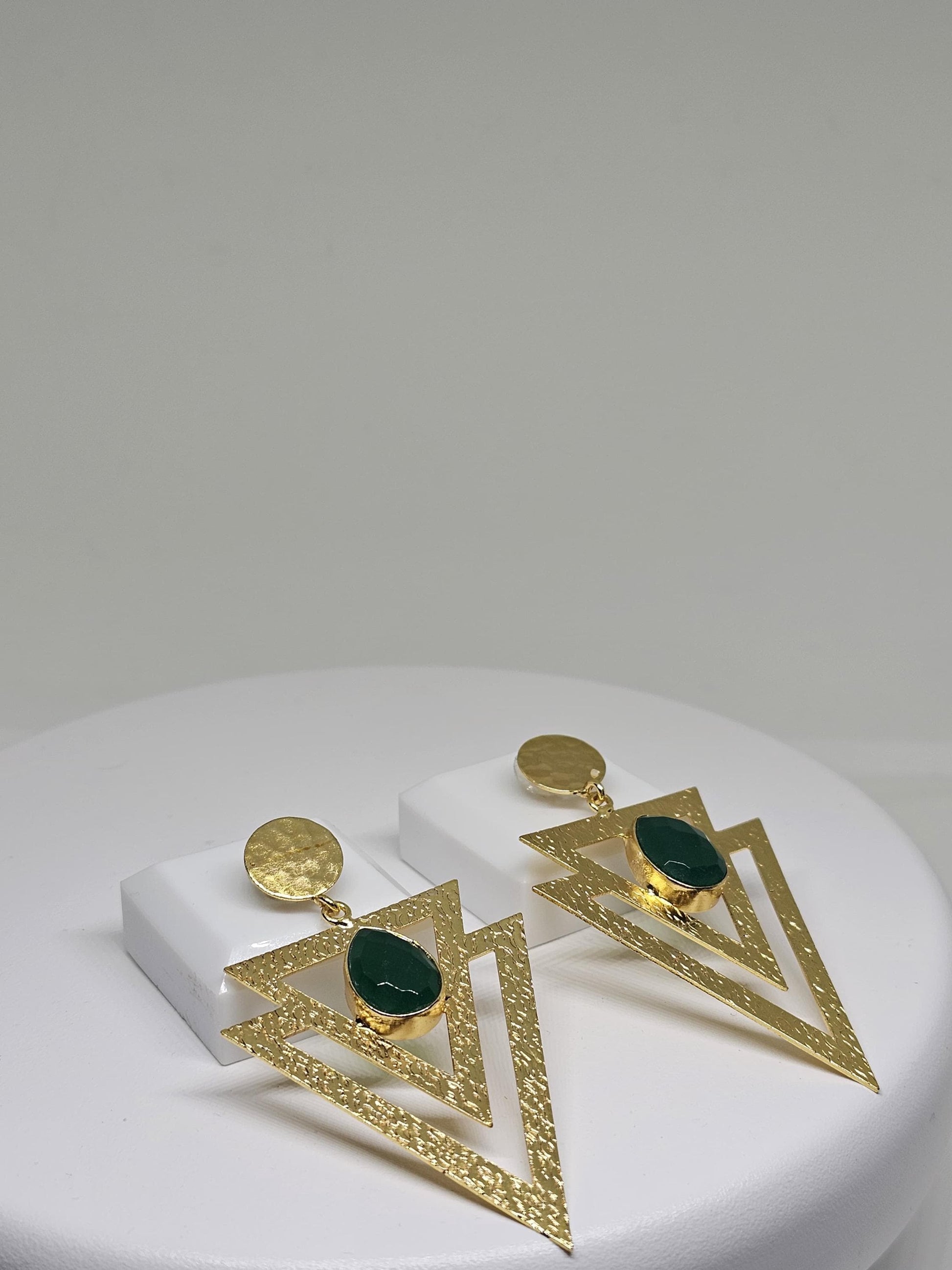 Geometric beaten brass earrings featuring layered textured triangles and a green teardrop-shaped stone, perfect for bohemian and statement looks