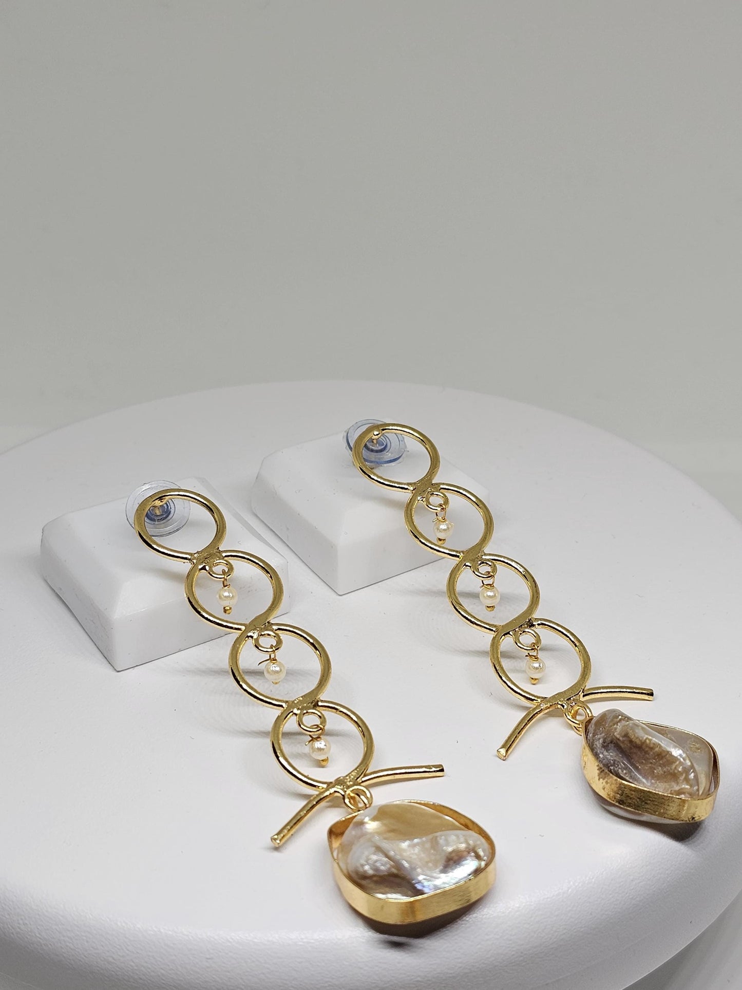 Beautifully designed gold earrings with interconnected circular motifs, adorned with pearls and a unique natural mother-of-pearl stone drop