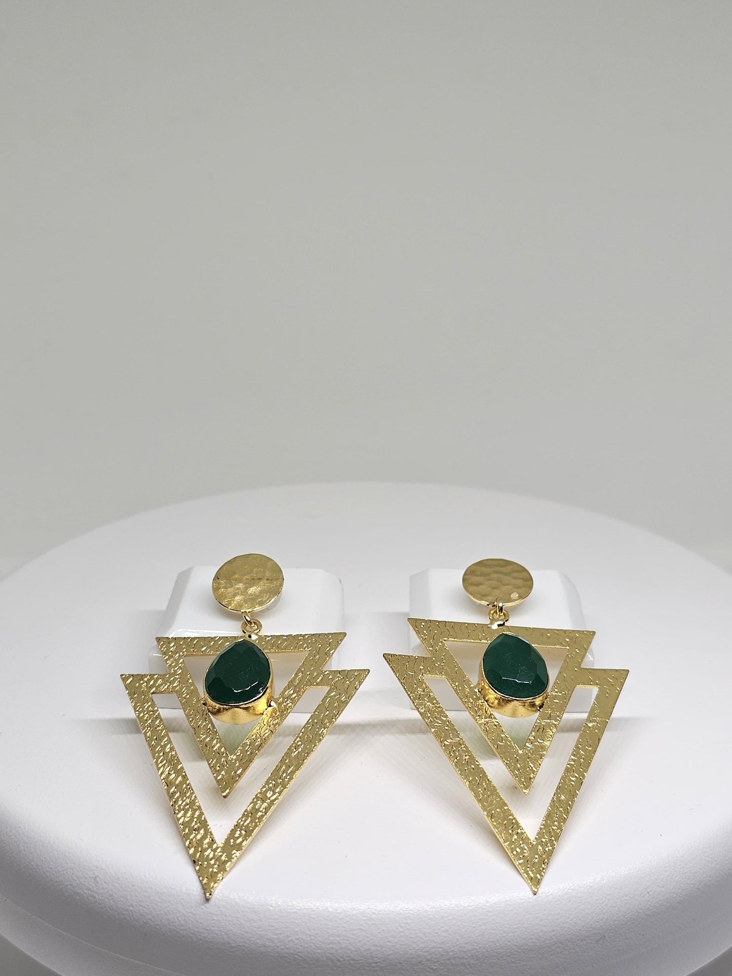 Geometric beaten brass earrings featuring layered textured triangles and a green teardrop-shaped stone, perfect for bohemian and statement looks